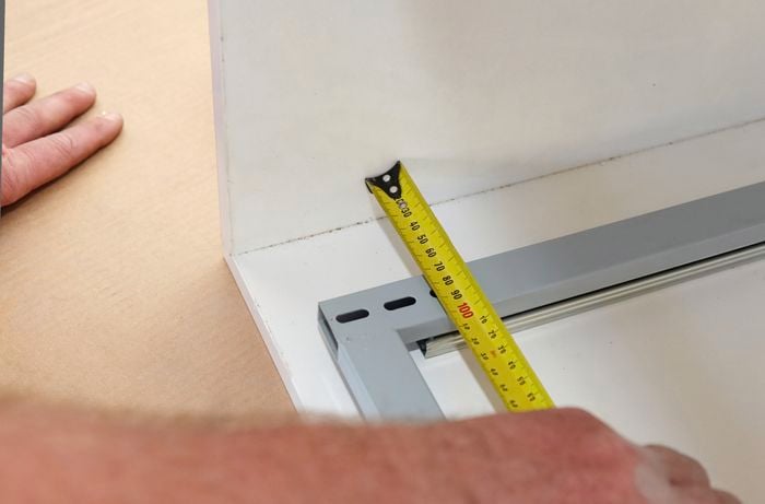 A tape measure used to position a shelving frame inside a cabinet