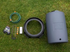 Tools and materials for installing a rainwater tank laid out on the grass.