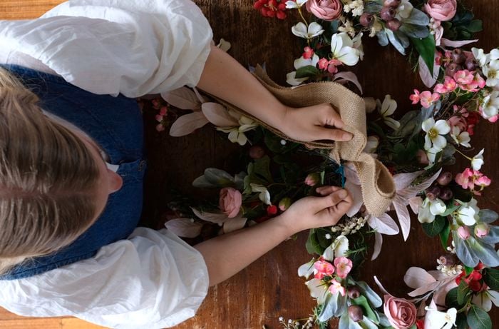 Birds-eye view of lady securing hessian bow to flower bow wreath using cable ties.