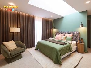 Bedroom with green accent wall, patterned headboard, and earthy decor.