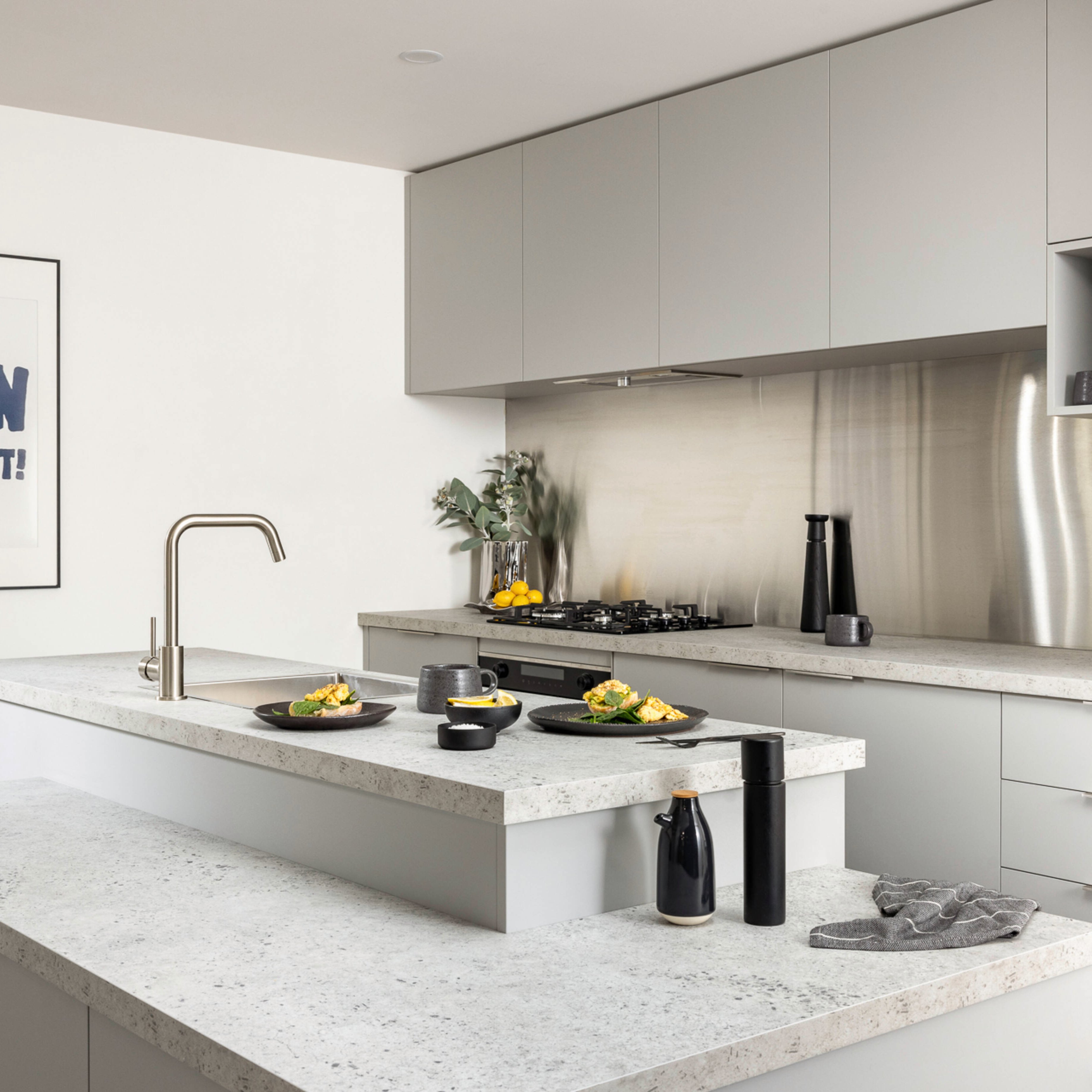 Light grey modern kitchen with a marble benchtop, black crockery and a coffee machine on the bench.