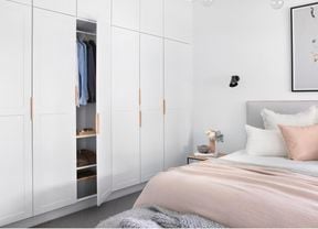 A white bedroom with a bed and floor to ceiling wardrobes.
