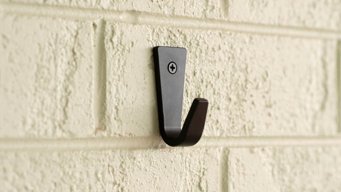 Black hook is securely mounted to a brick wall