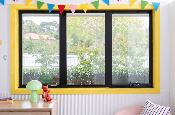 Bright yellow window trim in a kid-core room