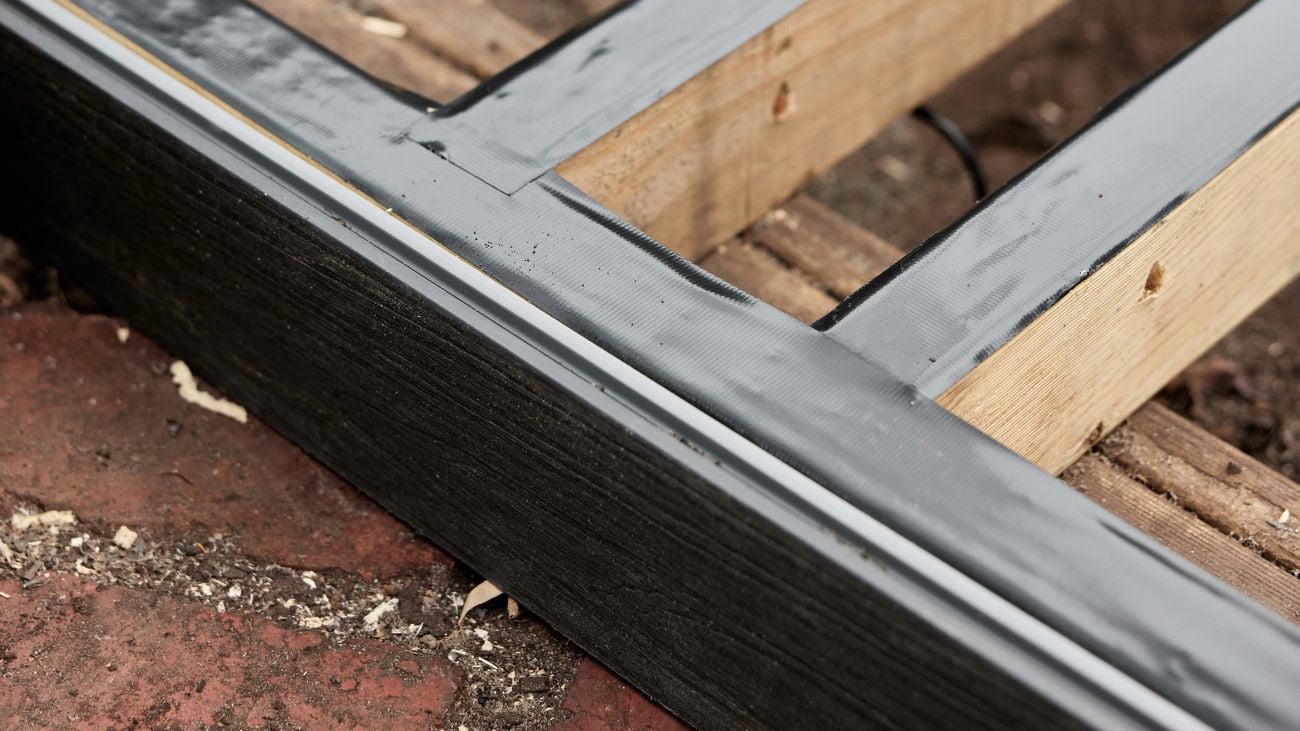 Timber joists laying on ground, sealed with black PVC joist tape