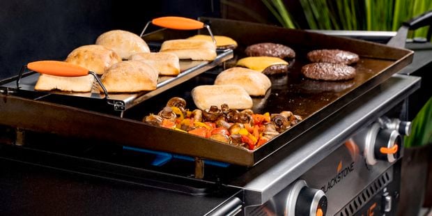Blackstone griddle with hamburgers, buns, cheese and mushrooms.