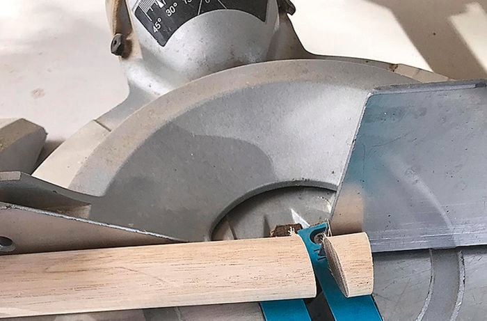 A mitre saw being used to cut dowel at a 15 degree angle