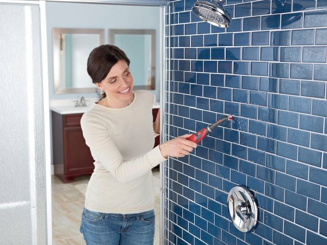 Woman cleaning shower.