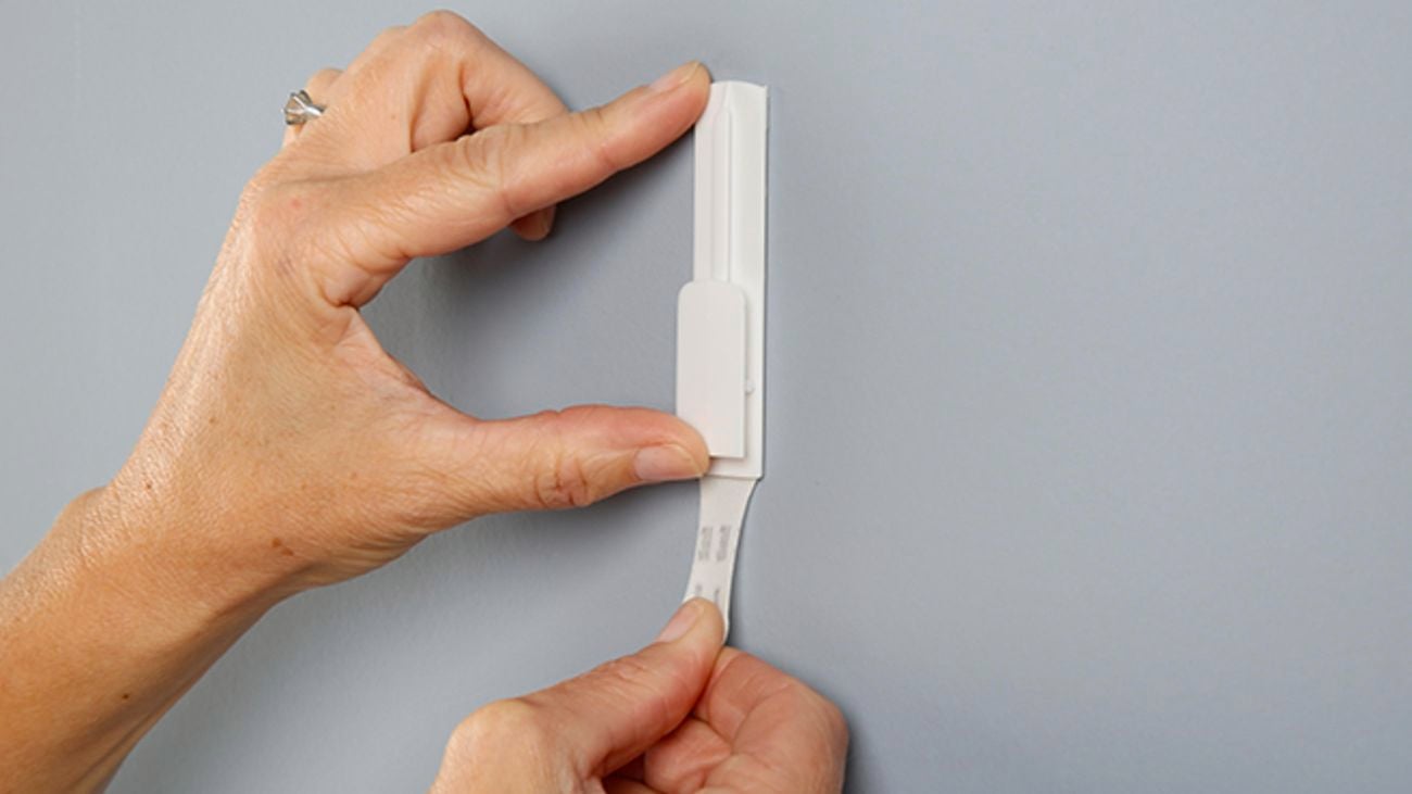Removing a removable picture hanger from the wall.