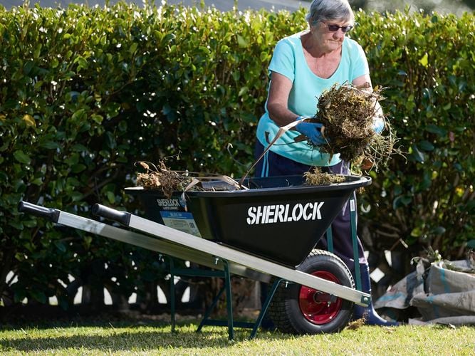 Person lifting garden waste from wheelbarrow