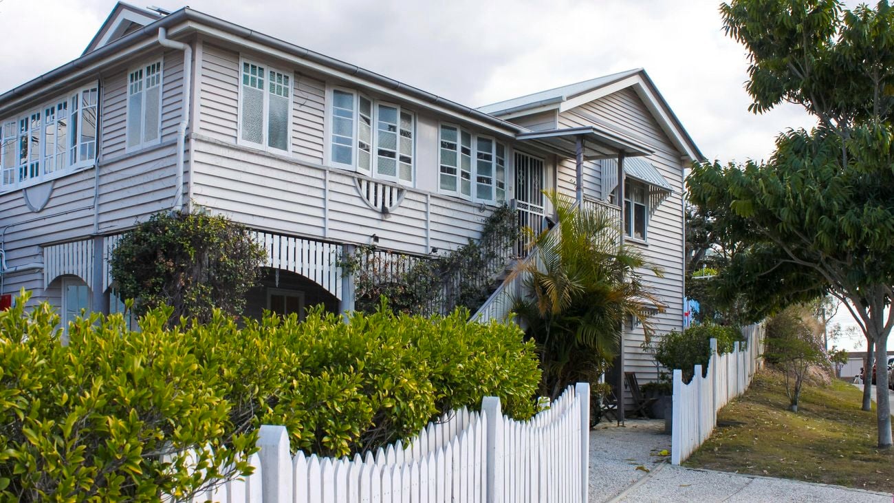Outside of white coastal home with shrubs and trees