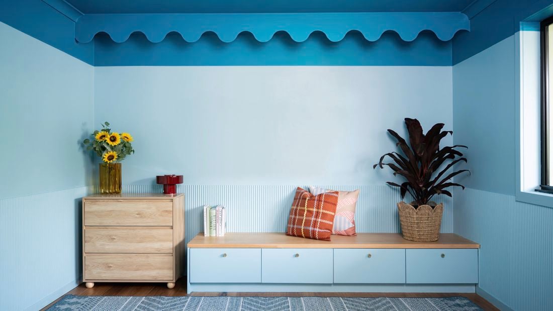 A modern room features a bold blue colour-capping design with decorative scalloped trim along the top of the wall.