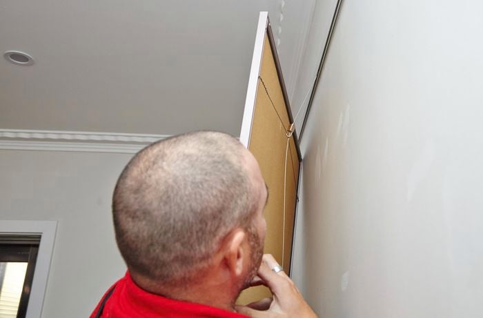 A Bunnings team member checking the length at which the hanging wire is hanging the picture attached to it