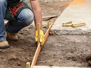 A man holding a piece of timber against the ground