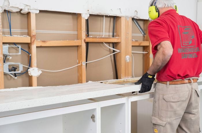A Bunnings Team Member is carefully removing a kitchen benchtop.