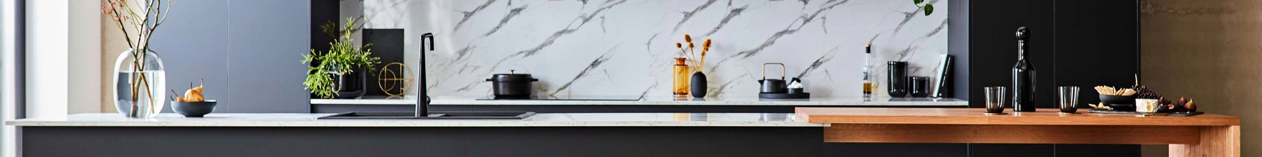 Kitchen with black benches and marble splashback.