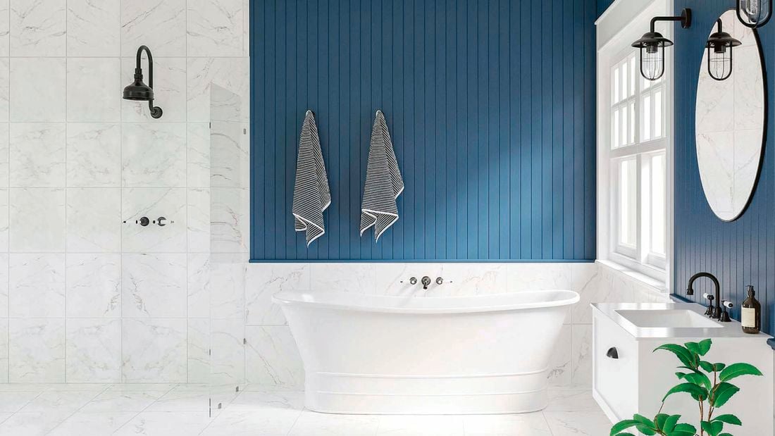 Bathroom with blue panelled wall, white marble tiles and black accessories.