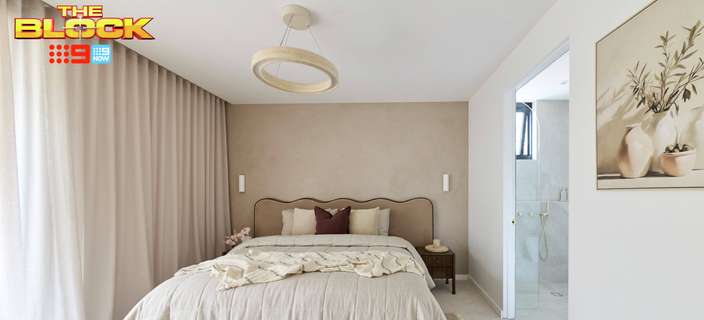 Neutral bedroom featuring a timber bed with soft beige bedding, floor-to-ceiling curtains, pendant light and adjoining ensuite.