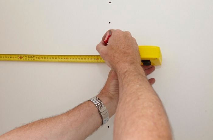 A tape measure being used to mark a kitchen pantry wall
