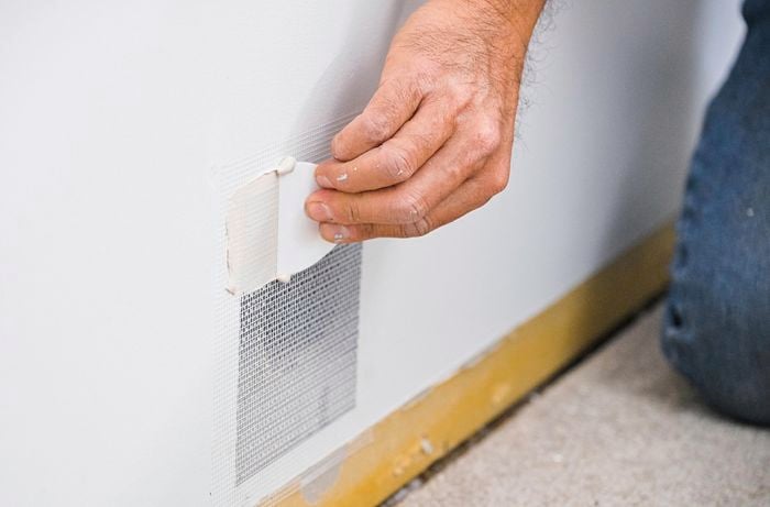 A person peeling tape off a wall
