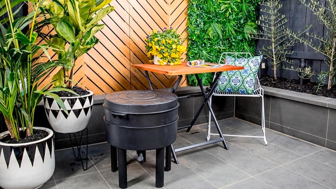 A round worm farm on legs in an outdoor room with furniture and potted plants