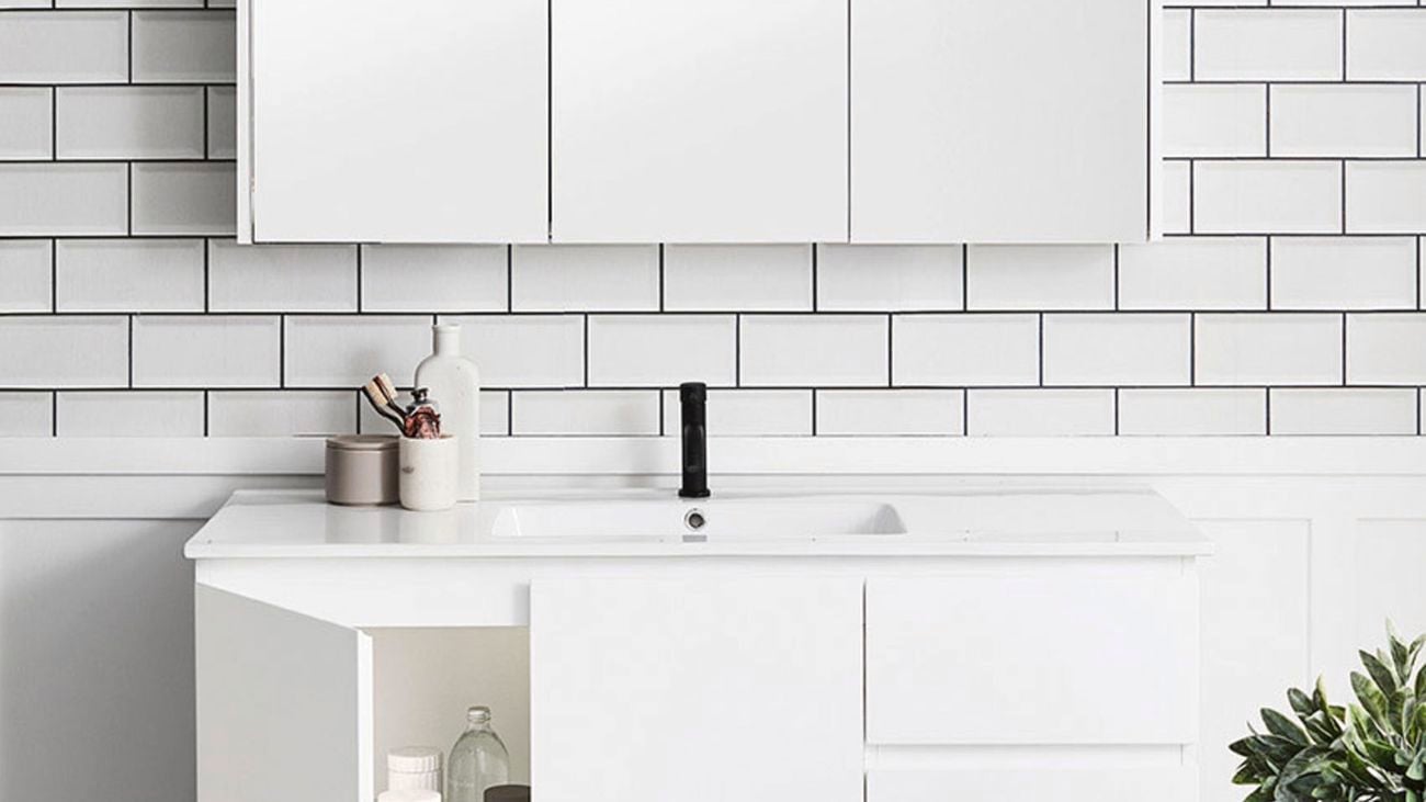 A white on white bathroom featuring subway tiled wall, light timber flooring, and a large shaving cabinet.