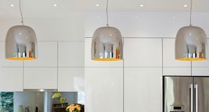 A white kitchen with three pendant lights hanging from the ceiling above the kitchen bench.