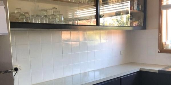 A kitchen with a white tiled splashback and black cabinets