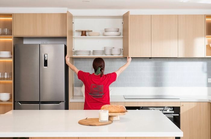 A Bunnings Team Member is looking on the kitchen cabinet filled with crockery.