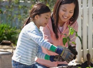 Lady and young girl in the garden together planting edible plants