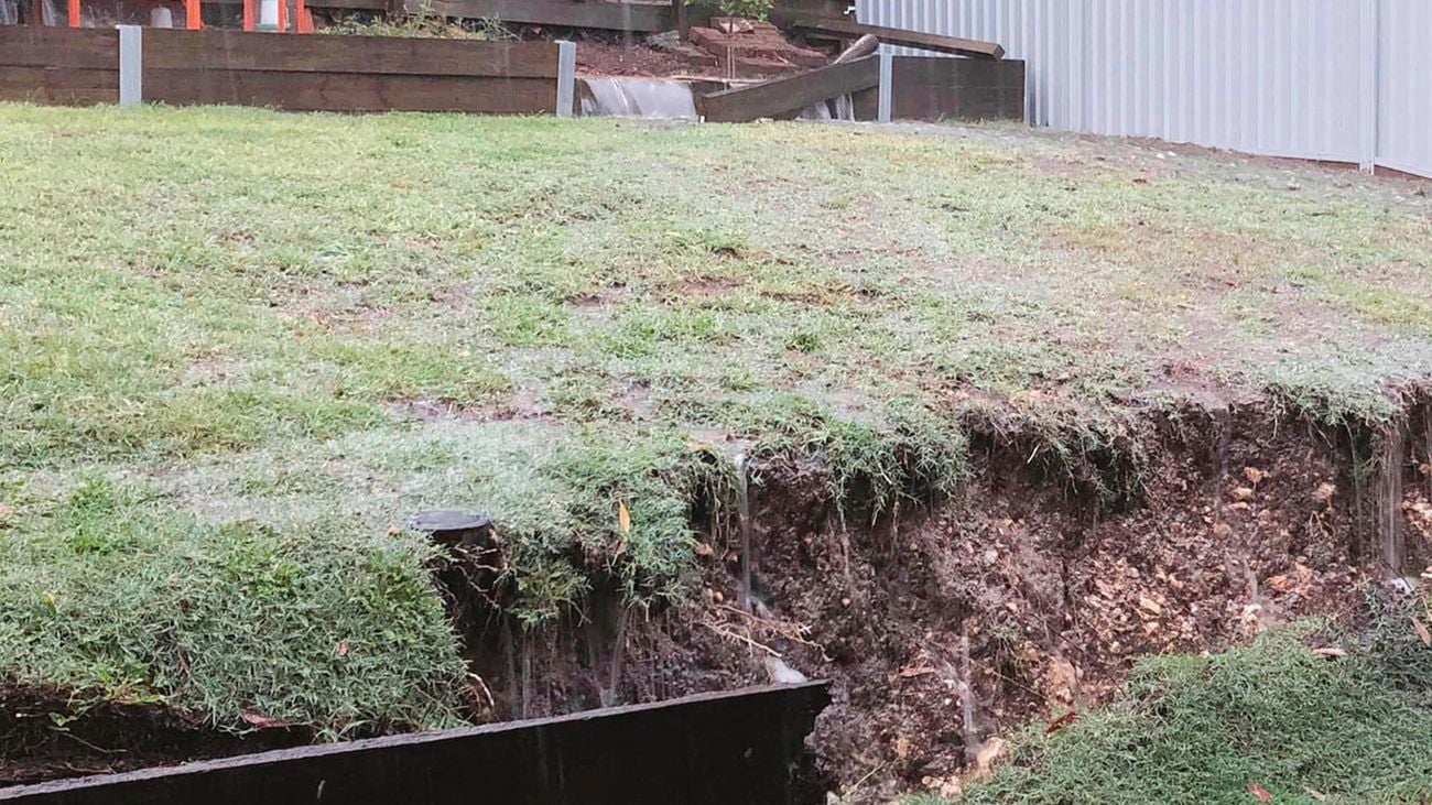 A sloping backyard with a large ditch dug out of it at the bottom
