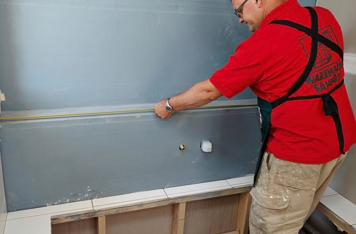A tape measure being used to measure a wall for applying tiles