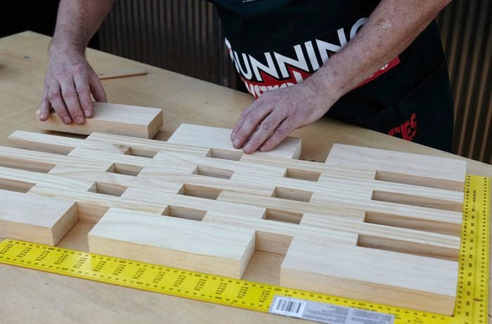 Person laying down pieces of wood in floor mat shape.