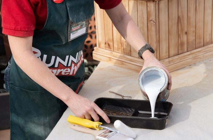Person pouring varnish into a paint tray