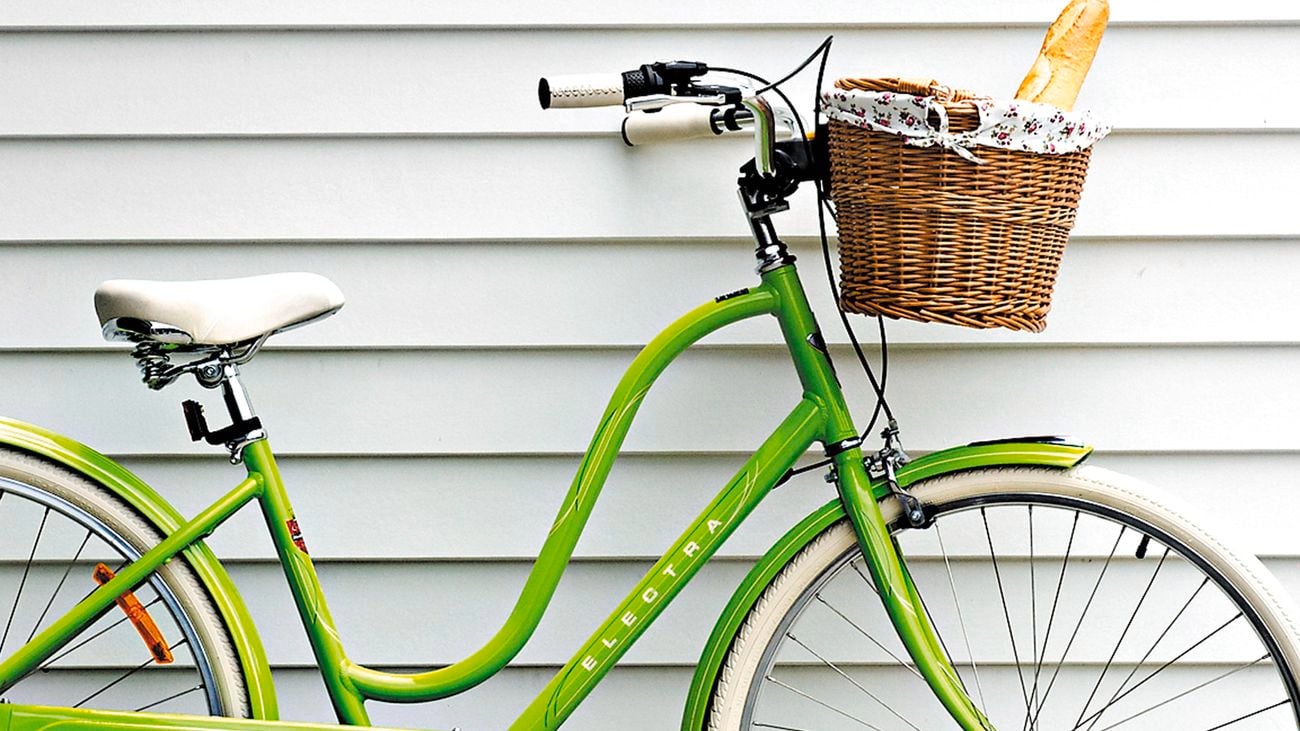 A green bike leaning up against a white weatherboard house.