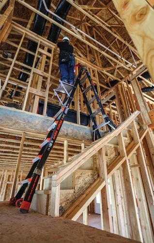Person on adjustable A-frame ladder working on timber wall frame