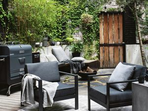 Outdoor lounge with two chairs and a BBQ next to it.