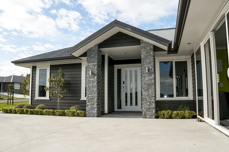 Exterior of a dark grey weatherboard house with a white front door