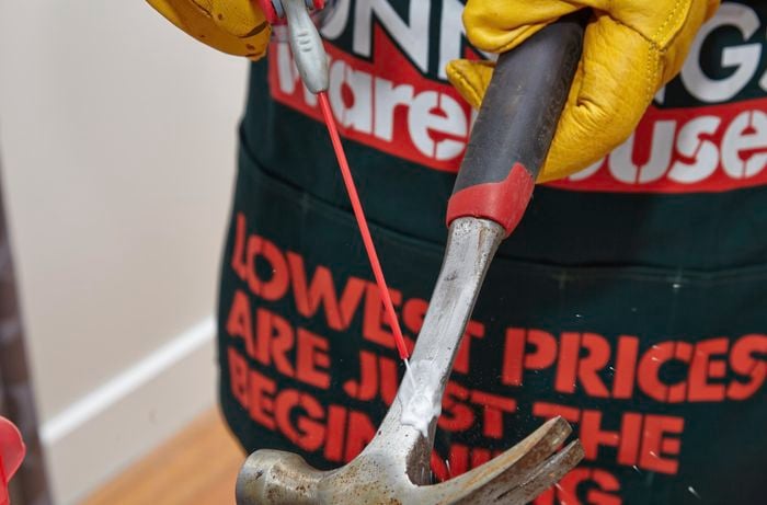 A person spraying a hammer with protective lubricant