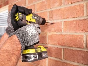 Person drilling into a brick wall.