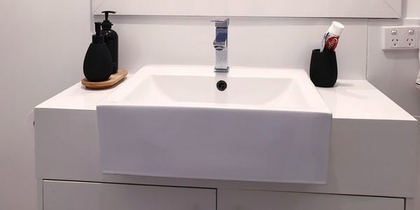 White bathroom with a ceramic sink, mirror and vanity cabinet