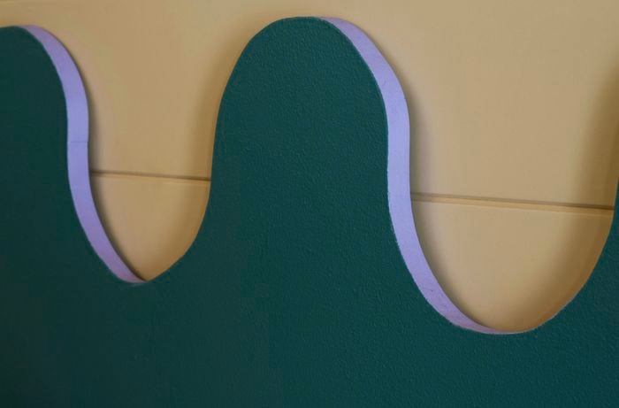 Close-up view of view of purple detail on wavy bedhead against wall