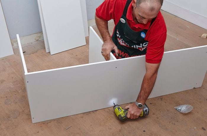 Person drilling side piece of wardrobe insert unit in place.