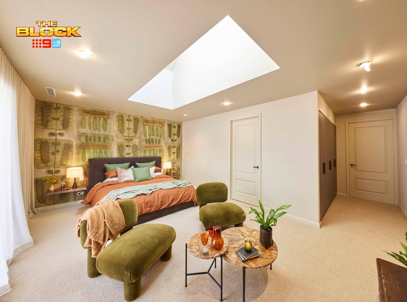 Bedroom with skylight, green chairs, and earthy-toned bedding.