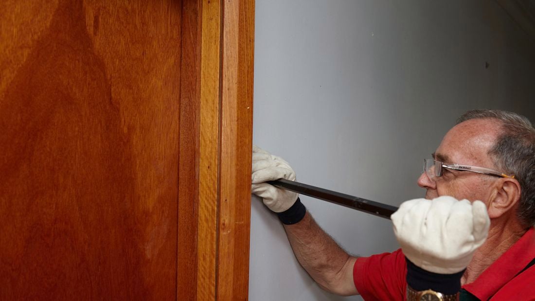 A Bunnings team member using a pry bar to remove an architrave