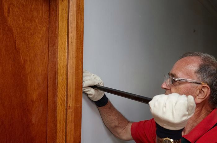A Bunnings team member using a pry bar to remove an architrave