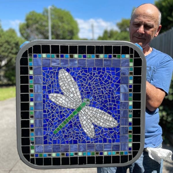 Man displaying square butterfly tile art outdoors.