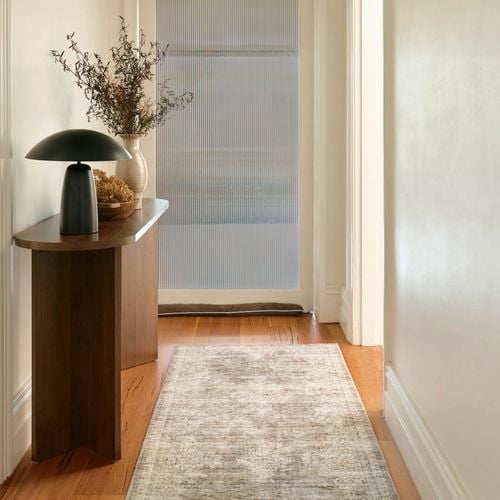 Narrow hallway with runner rug, console table, and sheer door curtain