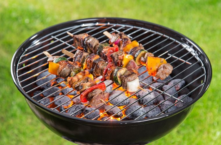 Kabobs grilling on a portable barbecue fueled by heat beads