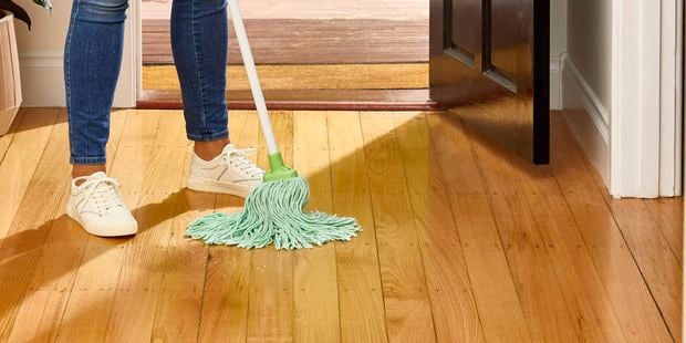 A person mopping timber floor with an Oates Greentex mop